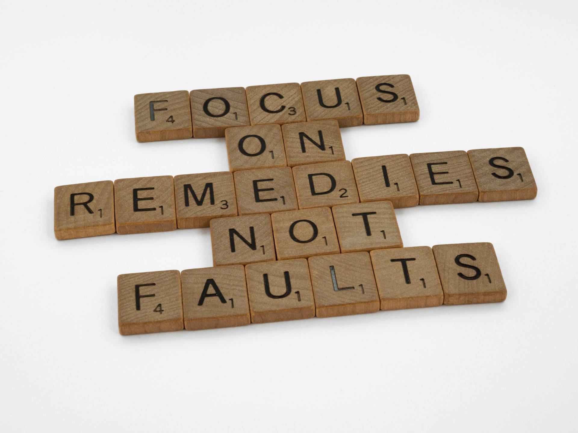 Wooden letter tiles arranged to read, “Focus on remedies, not faults.”
