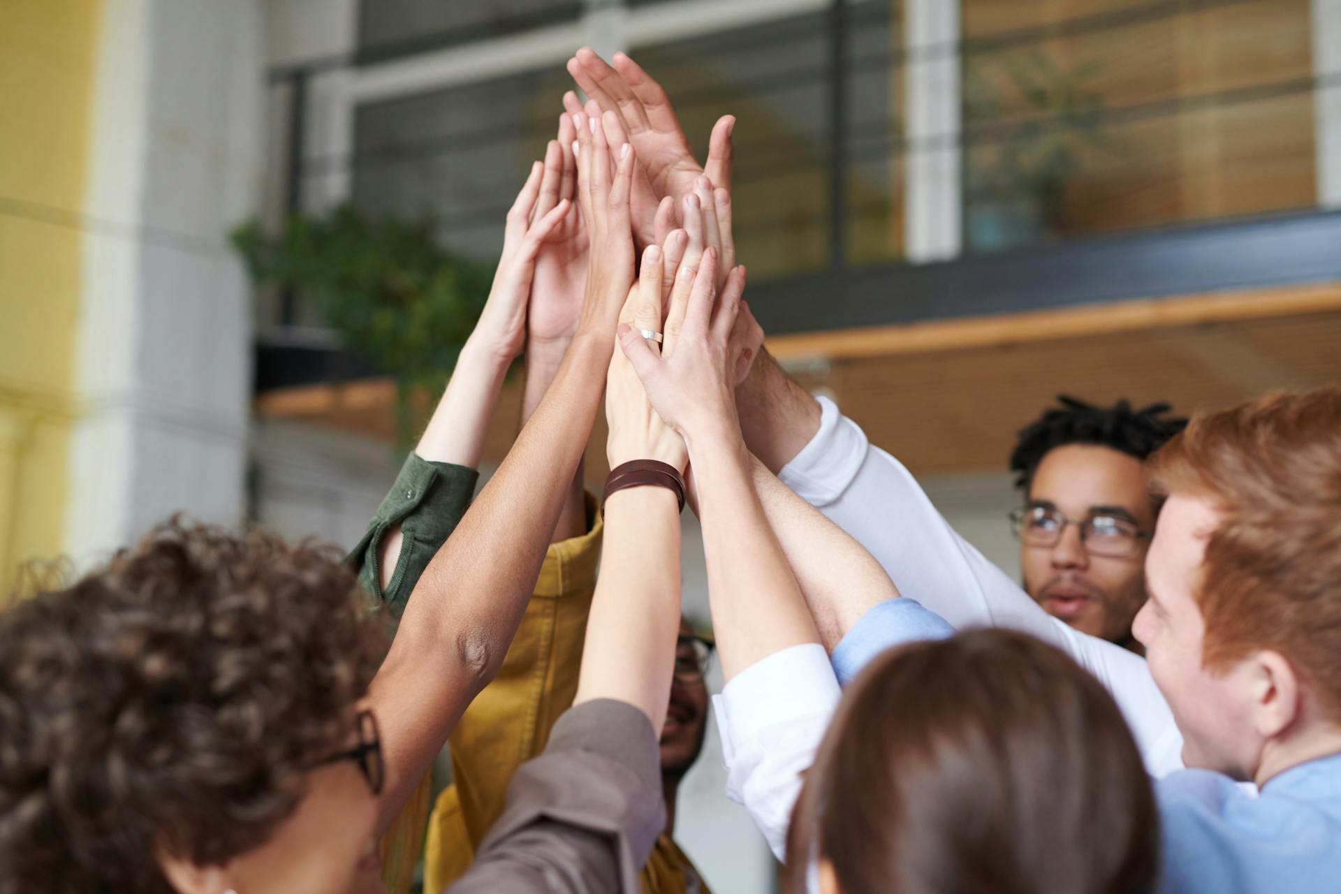 Coworkers place their hands together in a team huddle during an office meeting.